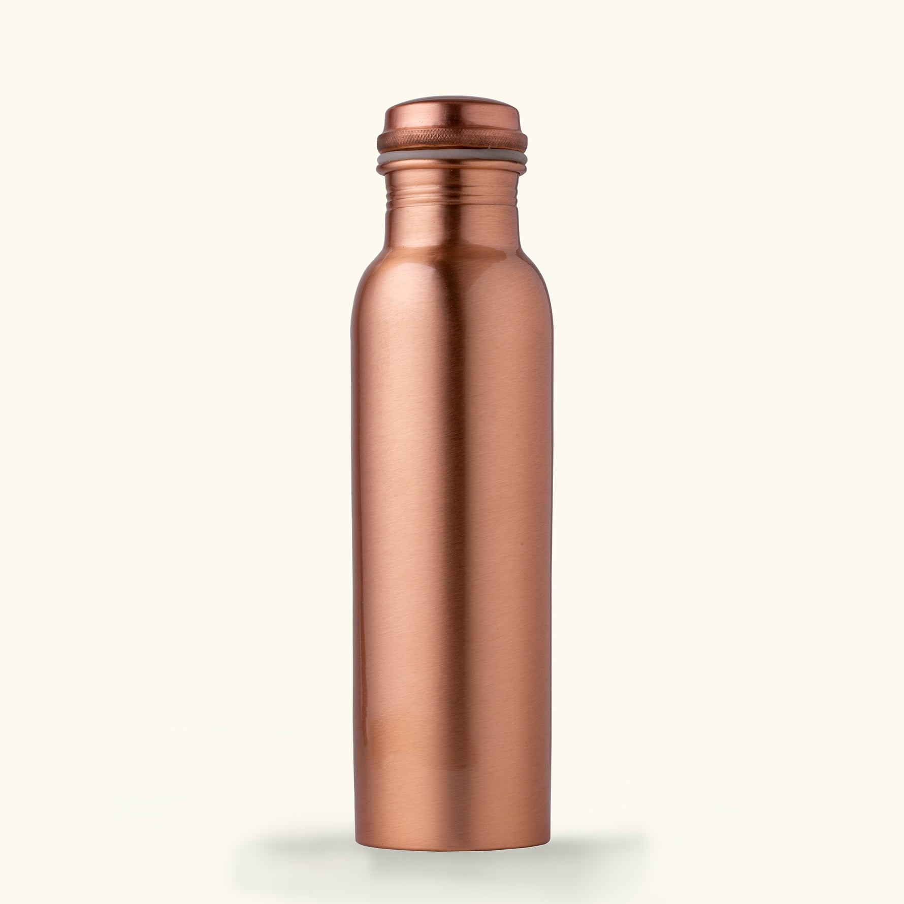 Image showcasing the Art of Vedas Copper Glass Bottle Set, featuring a 950ml copper bottle with a smooth, shiny finish and two complementary copper glasses, all arranged on a wooden table. The set reflects a warm, amber glow, emphasizing its elegant and traditional design suitable for health-focused hydration. Shop Ayurveda Oral Care Online